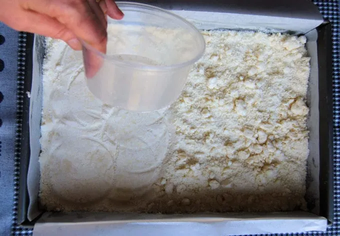 pressing shortbread crust into a pan.