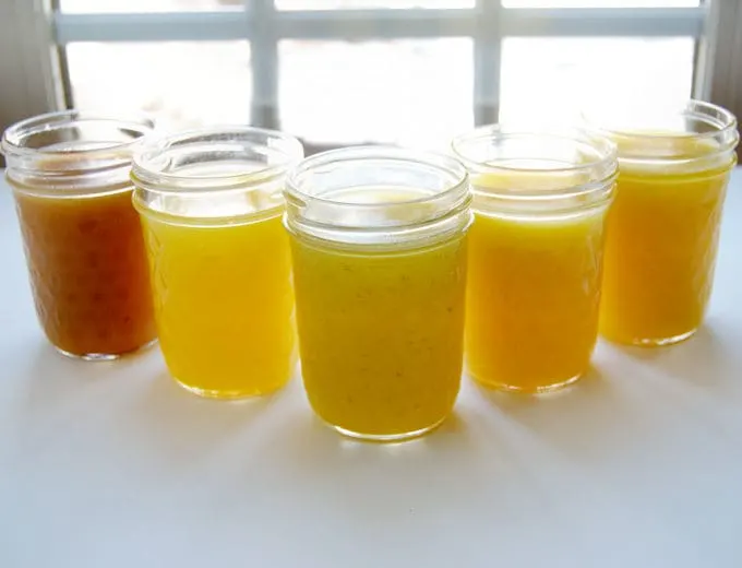 5 jars of fruit curd in front of a well lit window