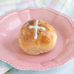 a hot cross bun on a pink plate.