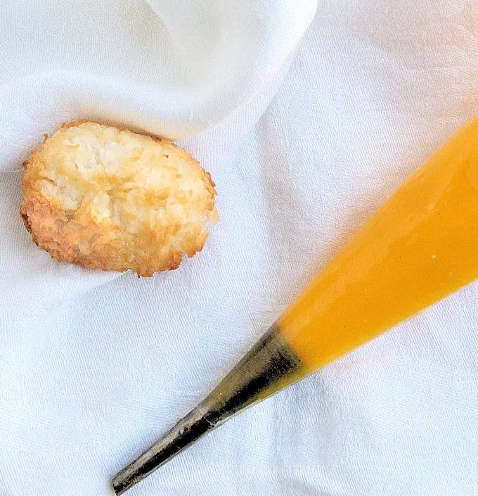 a coconut macaroon and a piping bag filled with passion fruit curd