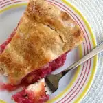 A slice of rhubarb pie on a white plate with a fork