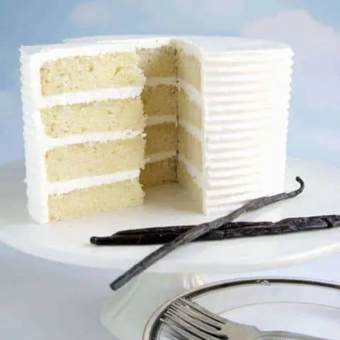 a four layer vanilla cake on a white cake stand