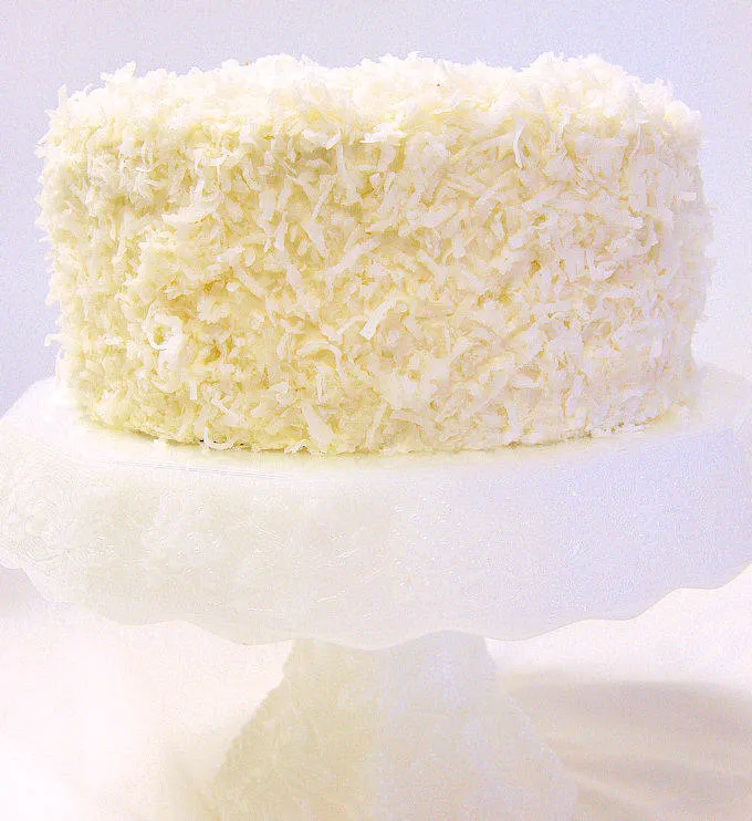 A coconut cake on a white cake stand