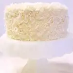 a coconut cake on a white cake stand