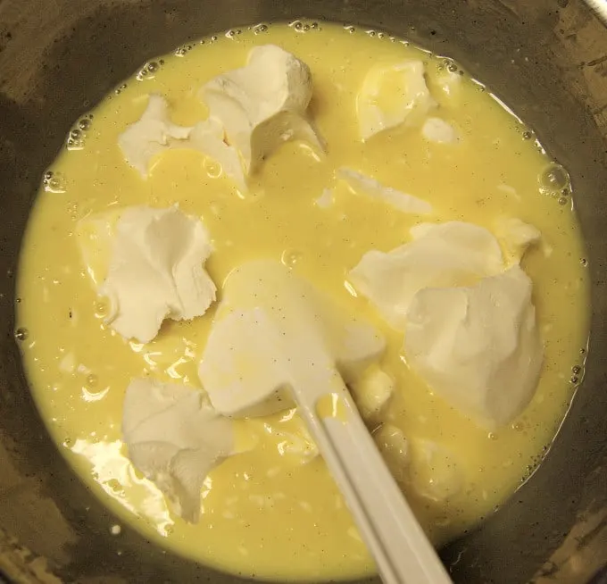 A bowl of custard with chunks of cream cheese.