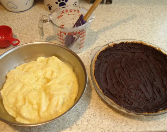 A chocolate lined pie crust and a bowl of banana pastry cream on a kitchen counter