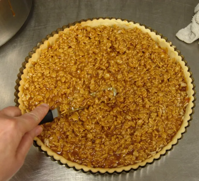 a tart shell filled with caramel and rice krispies