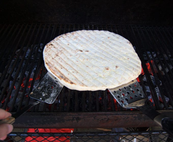 After the first size is lightly baked, use two large spatulas to flip the dough. It's ready for the toppings.