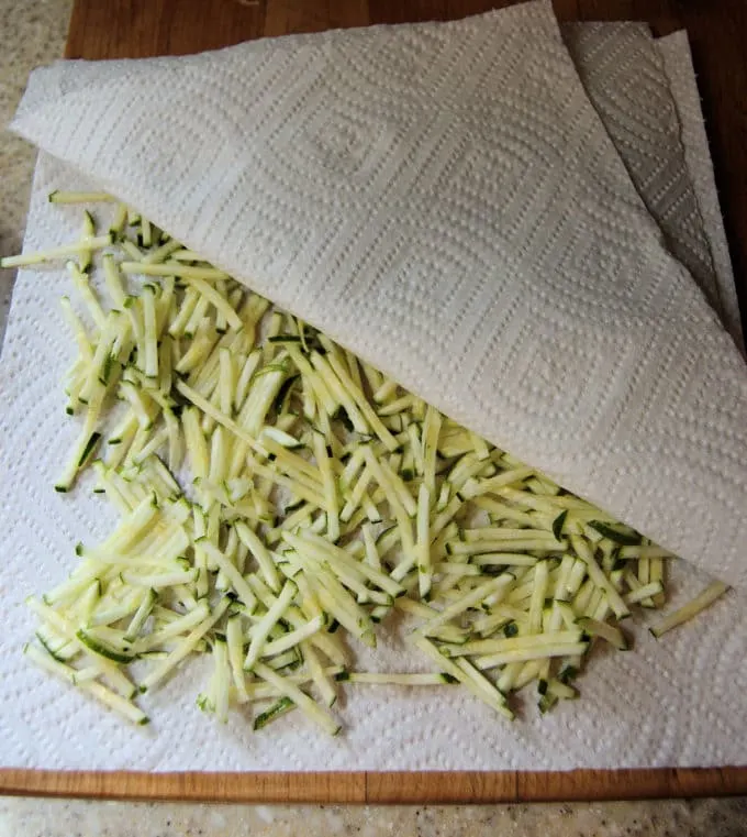 Layer the shredded zucchini between paper towels to absorb excess moisture.