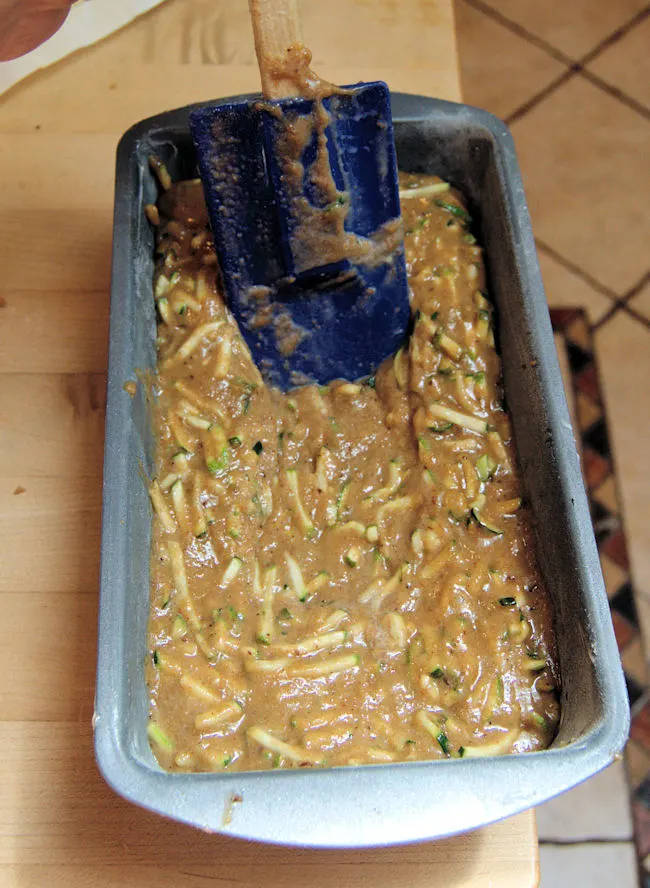 spreading zucchini bread batter into a loaf pan