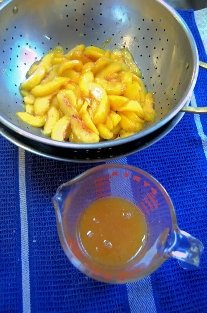 drained peaches in a sieve. A cup of peach juice.