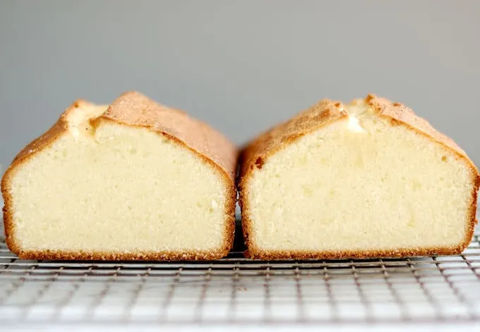 Two pound cakes side by side on a cooling rack with a gray background