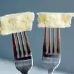 Two forks each with a bite of cake at the end. Gray background.