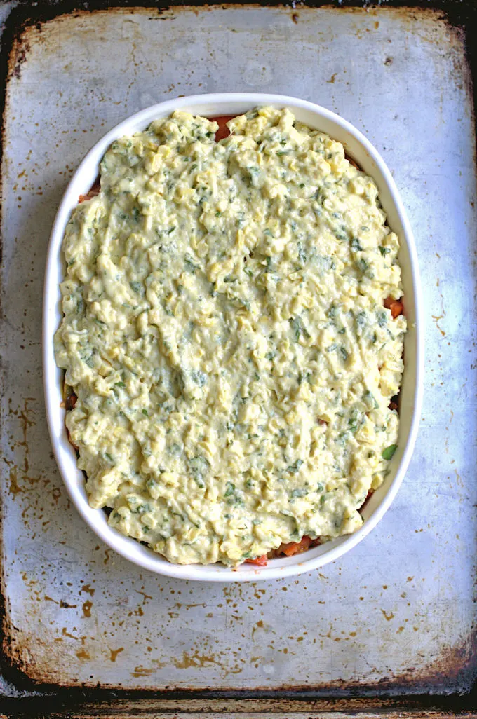 a tomato cobbler with cornbread topping ready for the oven