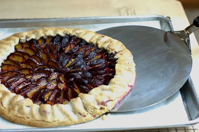 a plum tart sliding off a pan