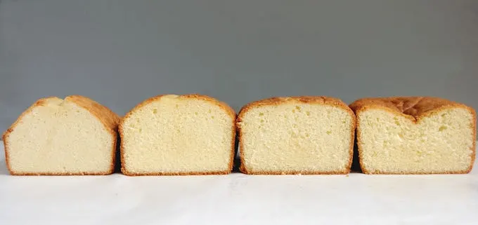 Four pound cakes standing side by side on a white surface with a gray background