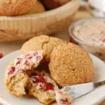 a plate of gingerbread scones with cranberry maple butter spread on one scone