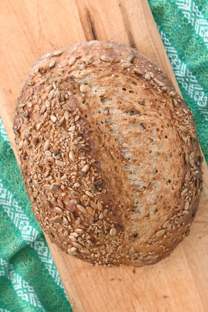 a loaf of cracked wheat bread on a cutting board