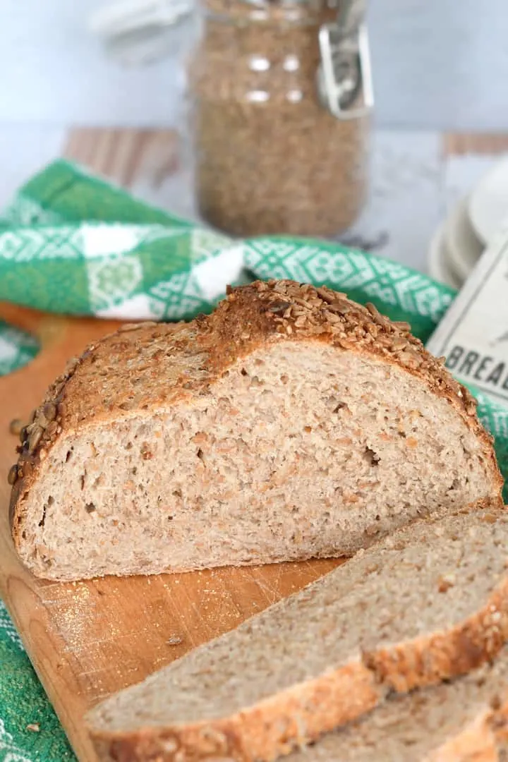 a sliced loaf of cracked wheat bread on a cutting board