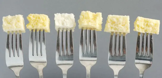 Six forks each with a bite of cake at the end against a gray background. Shows how in Cake batter eggs make a huge difference