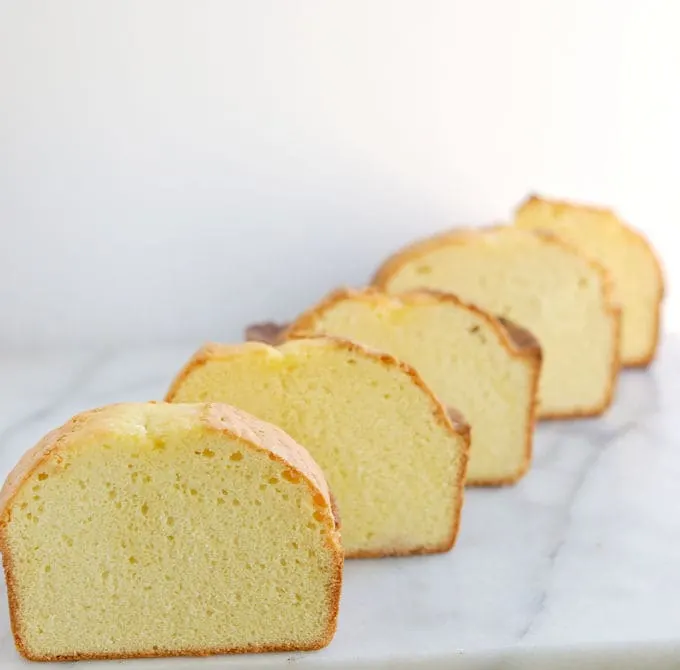 Five slices of pound cake lined up at a diagonal set on a marble board.
