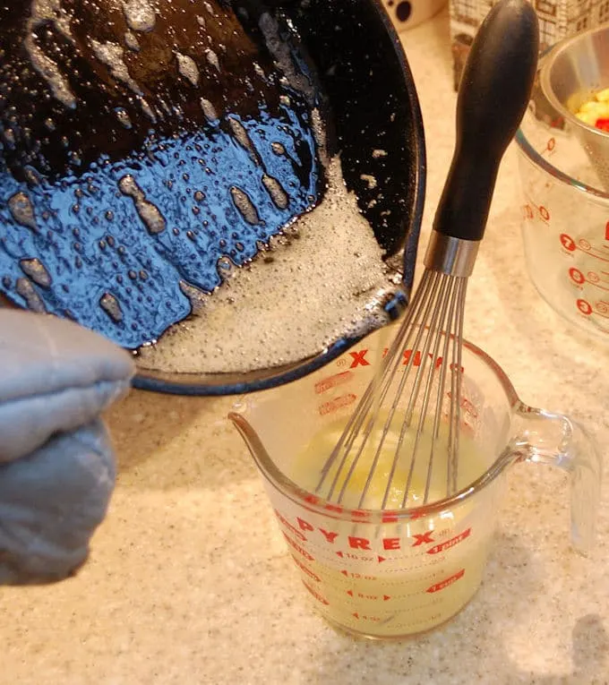 pouring melted butter from a cast iron skillet