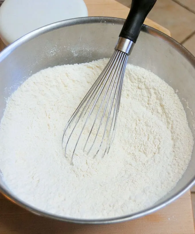 A bowl of flour with a whisk in the bowl.