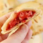 a hand holding a roasted strawberry hand pie