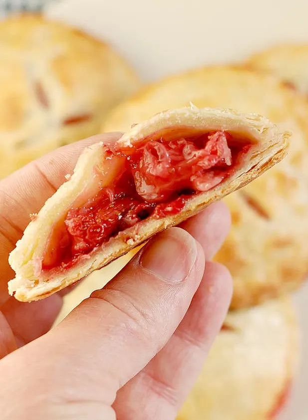 a hand holding a strawberry hand pie