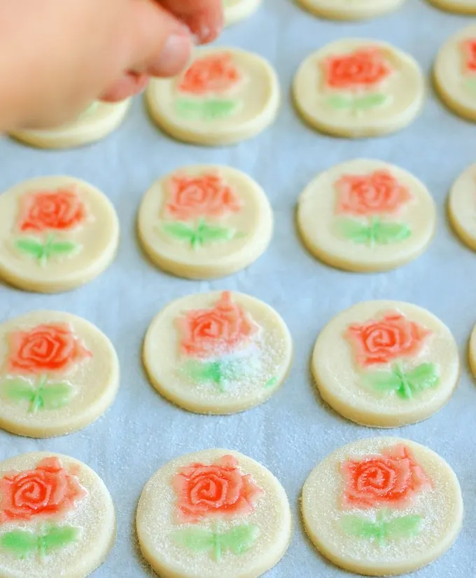 rose shortbread cookies getting sprinkled with sugar