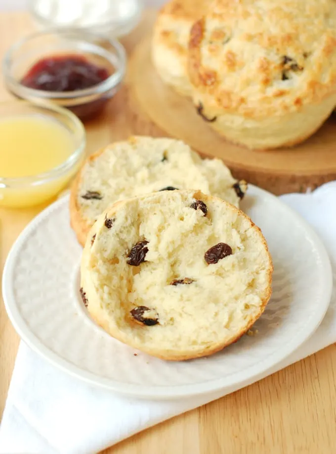 a raisin scone, slit open, on a white plate