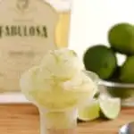 a bowl of caipirinha sorbet with a bottle of caipirinha in the background