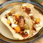 two pork tacos with peach salsa on a plate