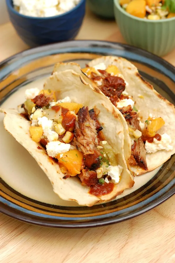 two pulled pork tacos with grilled peach salsa