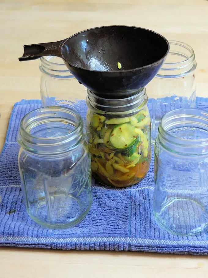 pickles in a jar with a canning funnel