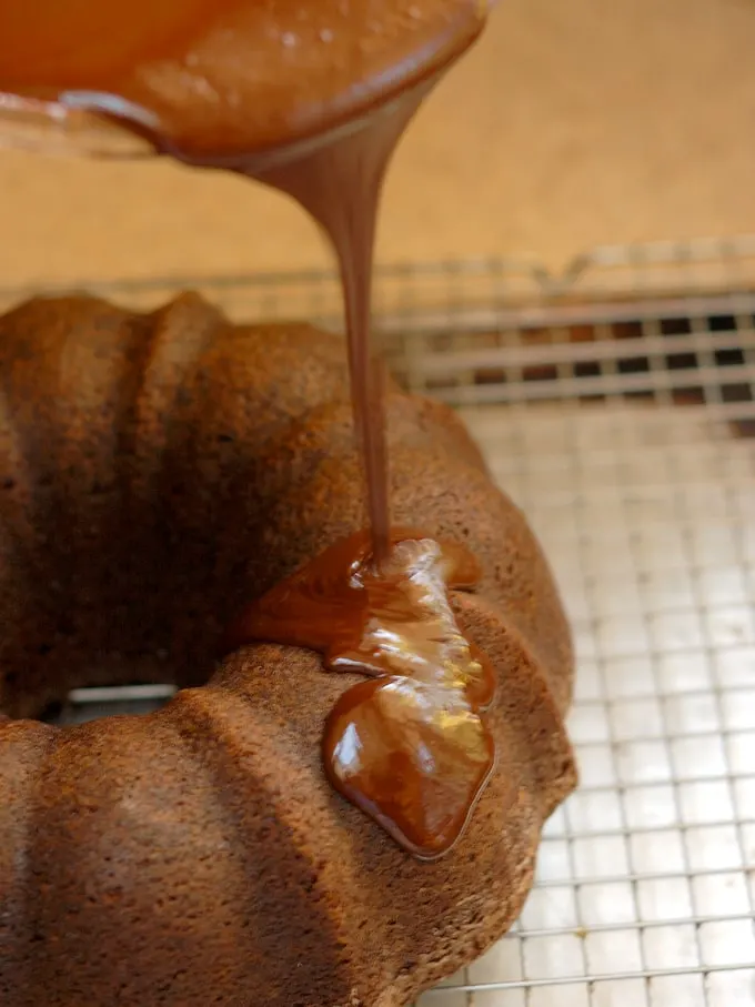 a chocolate bundt cake being glazed with chocolate ganache