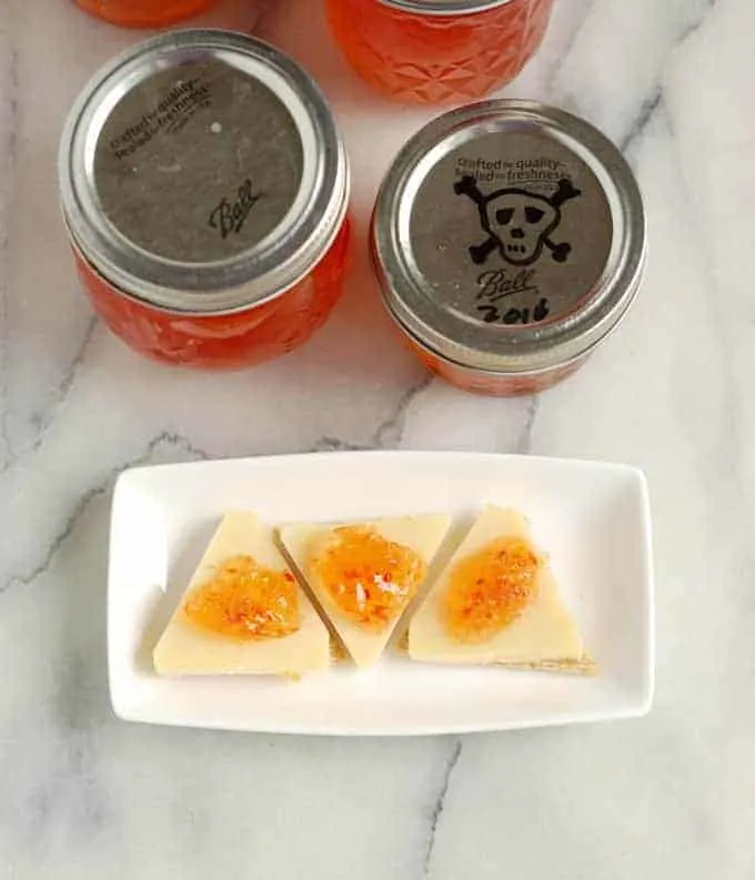 a plate with crackers and cheese with hot pepper jelly