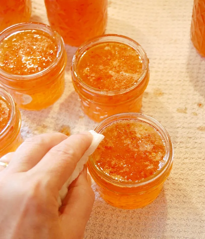 a hand cleaning the rim of a jelly jar