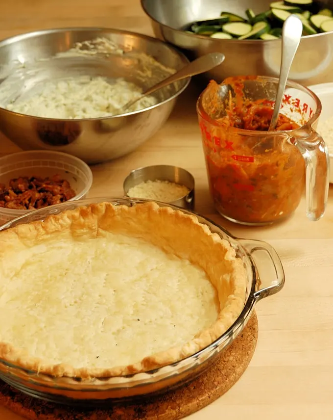 all the components of zucchini pie ready for assembly on a wood surface.