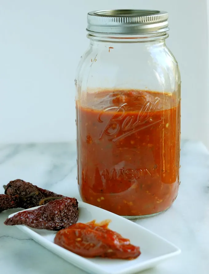 a jar of chipotles in adobo sauce and a plate with a pepper