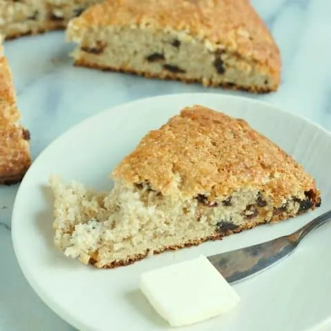 a wedge shaped spice and fruit scone on a white plate