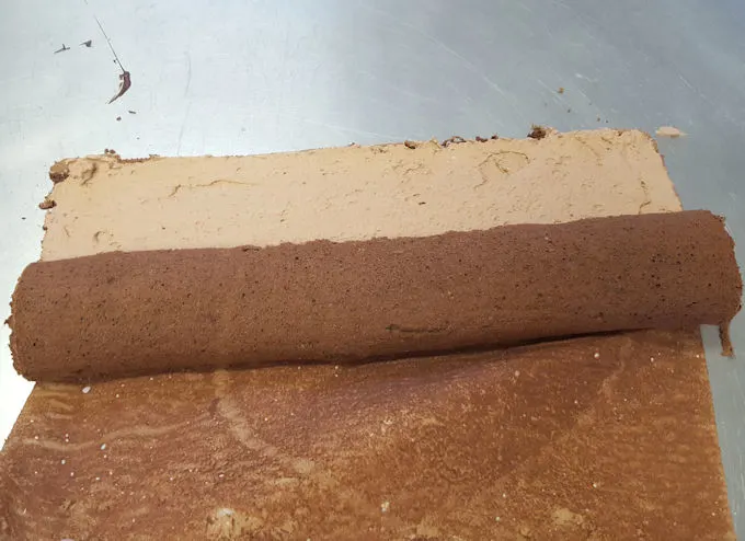 a partially rolled chocolate cake log