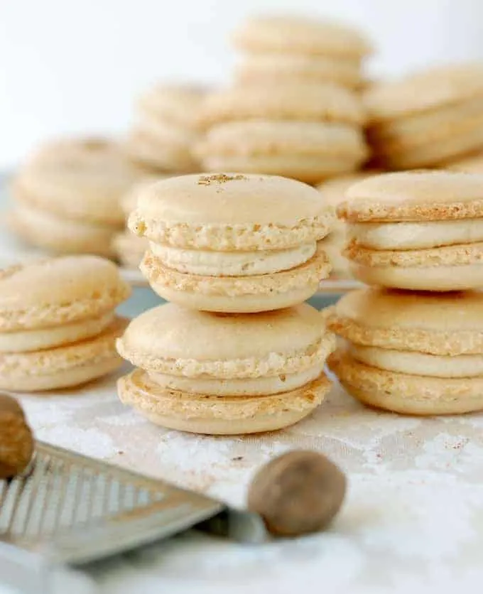 a closeup shot of eggnog macarons with nutmeg and a grater