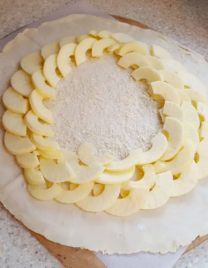 dough rolled for a galette with apple slices arranged in layers