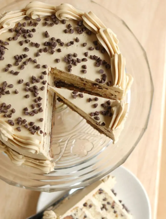 top view of a chocolate chip cookie cake iced with shell border on a glass cake stand