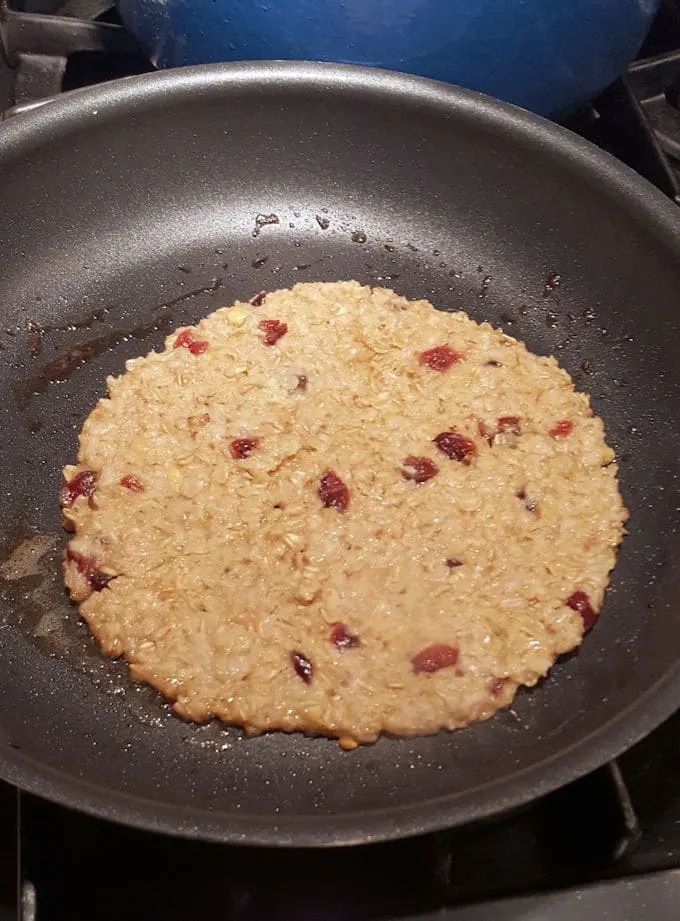 showing an oatmeal pancake frying in a pan
