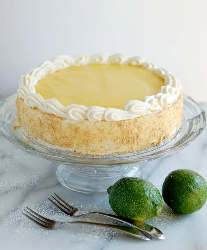 a lime layered cheesecake on a glass cake stand