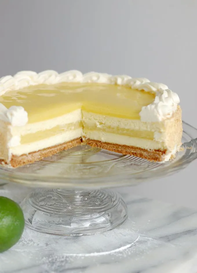 a partially cut lime layered cheesecake on a glass cake stand