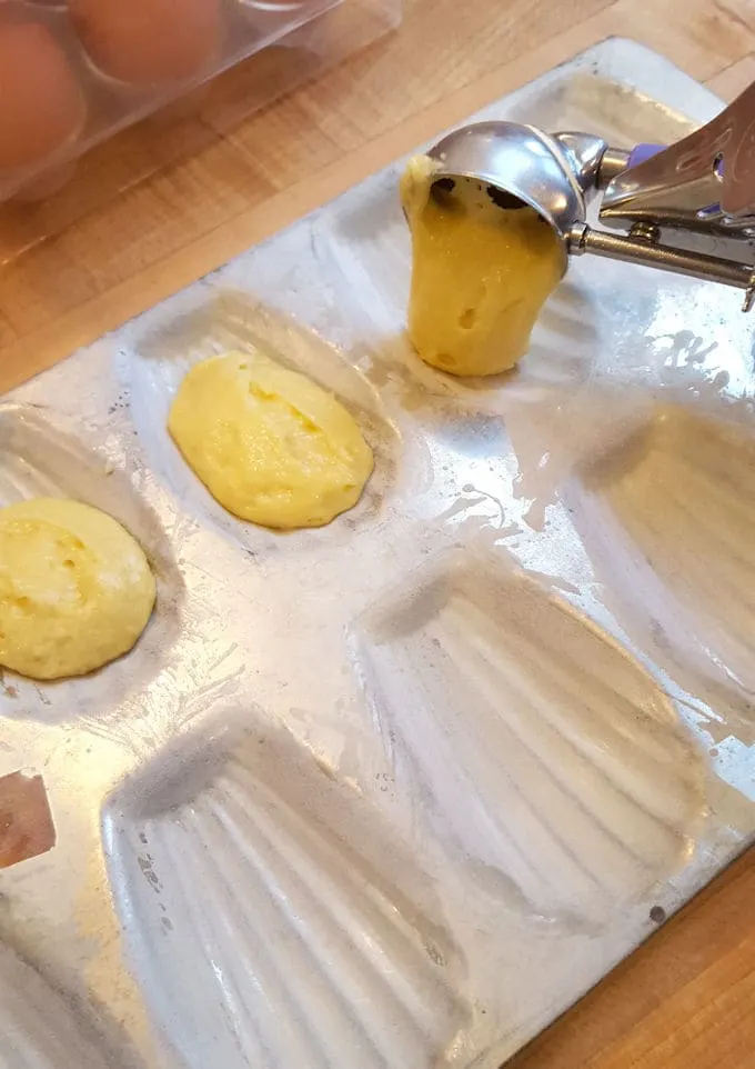 scooping batter into a madeleine pan