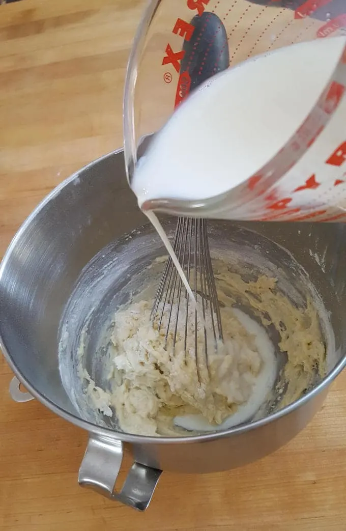 adding milk to dutch pancake batter in a deep bowl